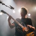 Gitarist spiller på en scene under sterke konsertlys