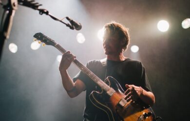 Gitarist spiller på en scene under sterke konsertlys