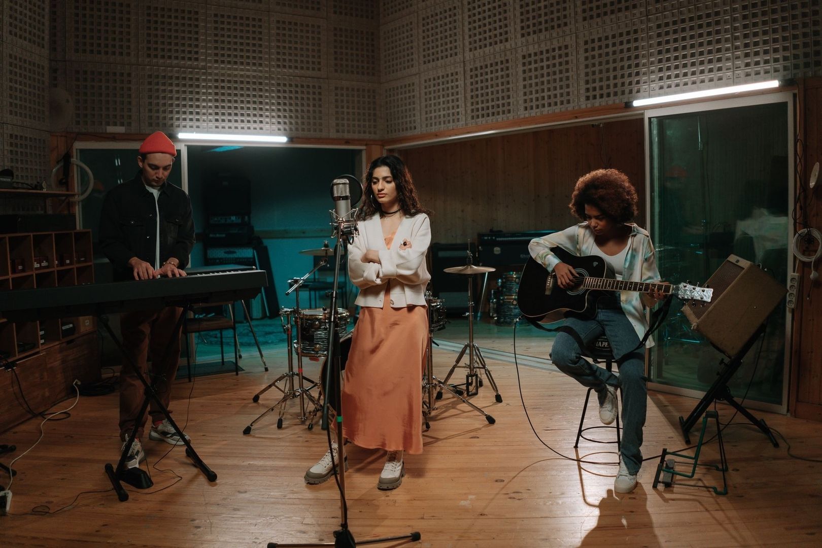 Tre musikere i studio, samlet rundt instrumentene før en øving