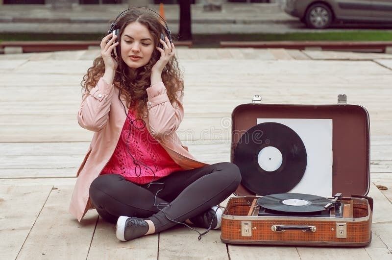 Person med hodetelefoner ved en platespiller og vinylplater